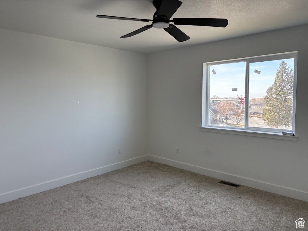 Carpeted empty room featuring ceiling fan