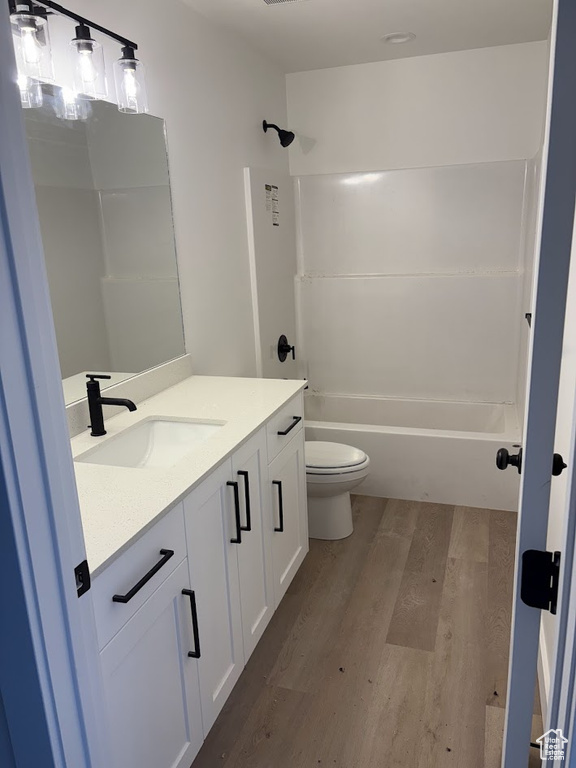 Full bathroom with vanity, hardwood / wood-style flooring, bathing tub / shower combination, and toilet
