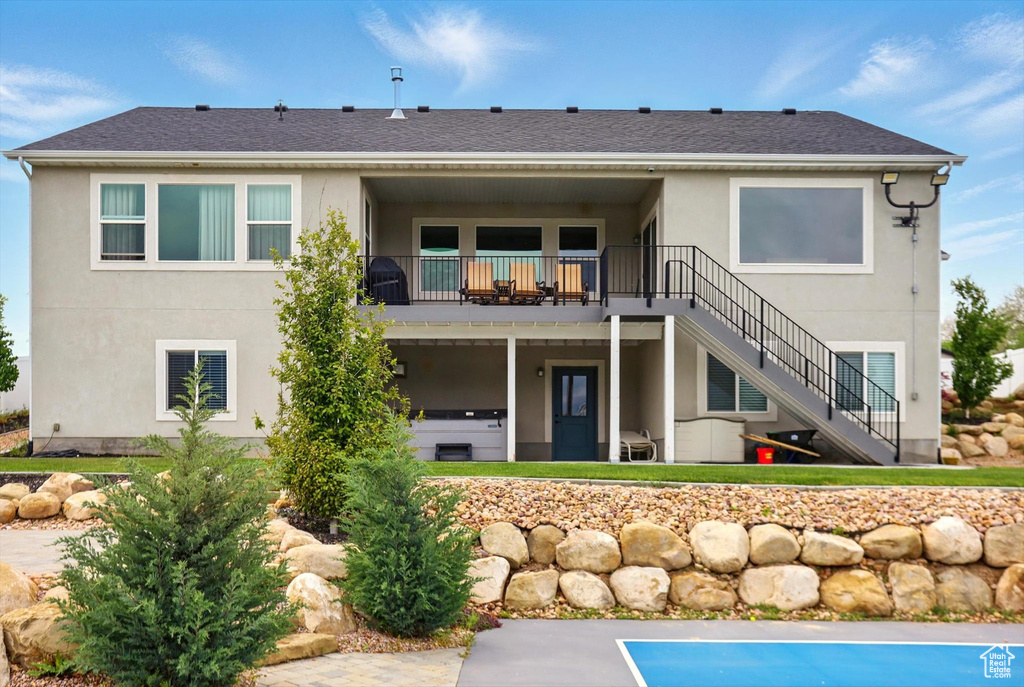 Rear view of house featuring stairs and stucco siding