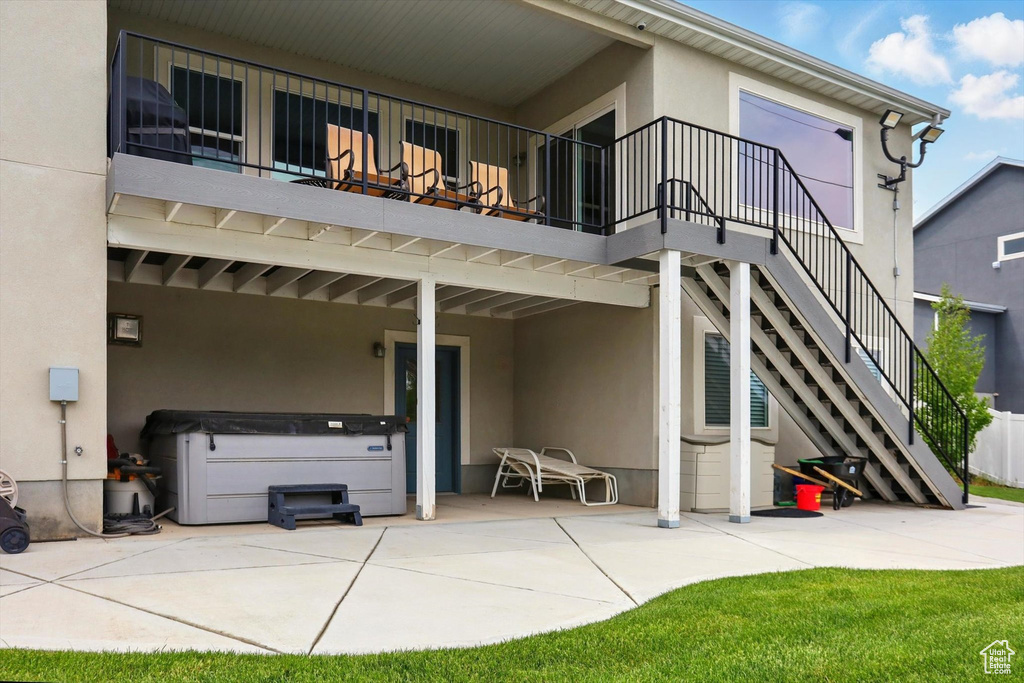 Rear view of property featuring a patio, a hot tub, stucco siding, and stairs