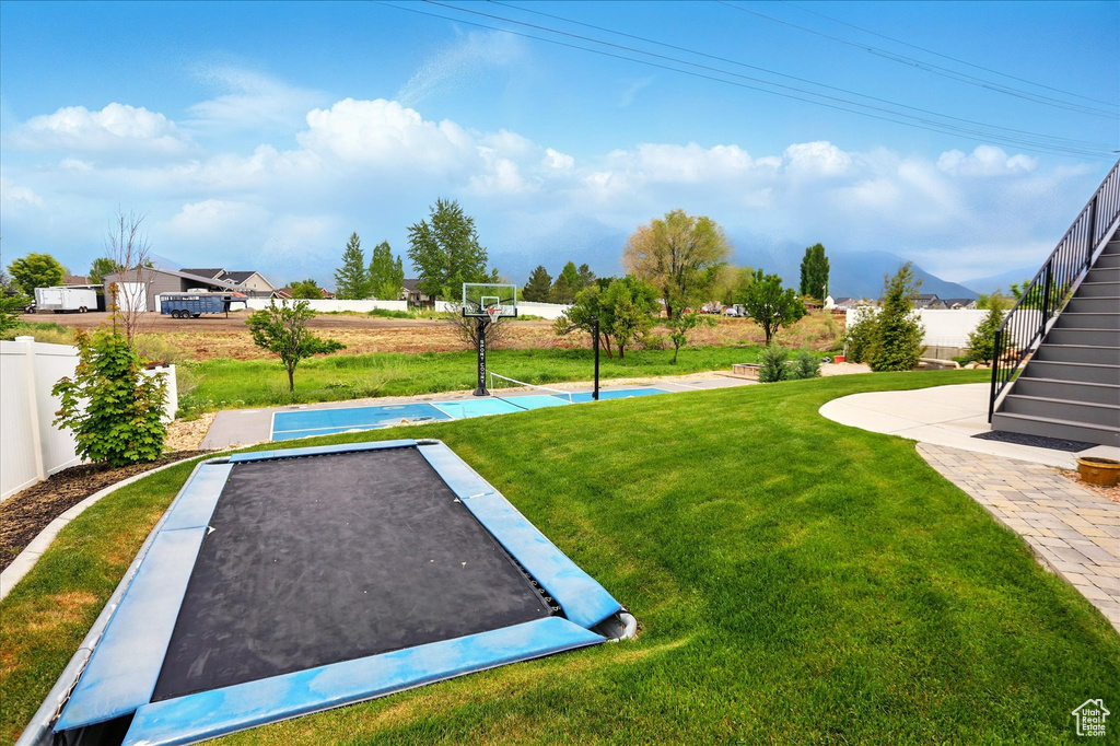 Exterior space with a yard, stairs, basketball hoop, and fence