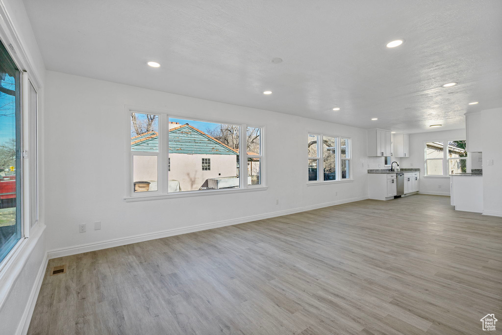 Unfurnished living room featuring sink and light wood-type flooring