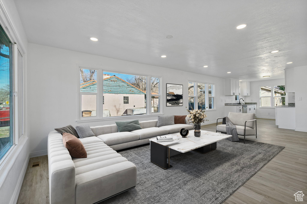 Living room featuring recessed lighting, visible vents, light wood-style flooring, and baseboards