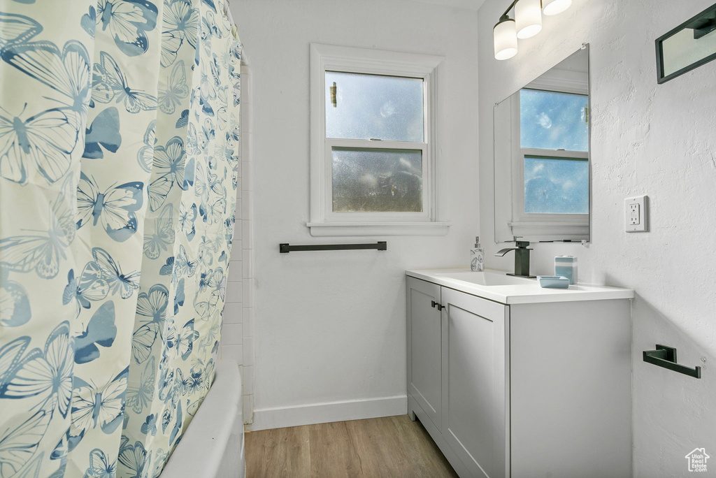 Bathroom featuring shower / bath combination with curtain, wood-type flooring, and vanity