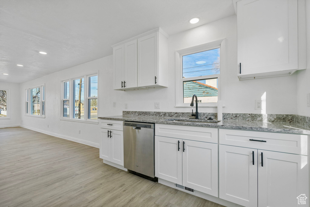 Kitchen with sink, white cabinetry, light wood-type flooring, dishwasher, and light stone countertops