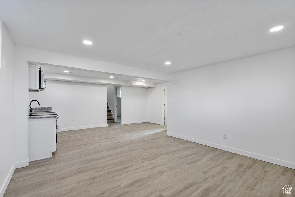 Unfurnished living room with sink and light hardwood / wood-style floors