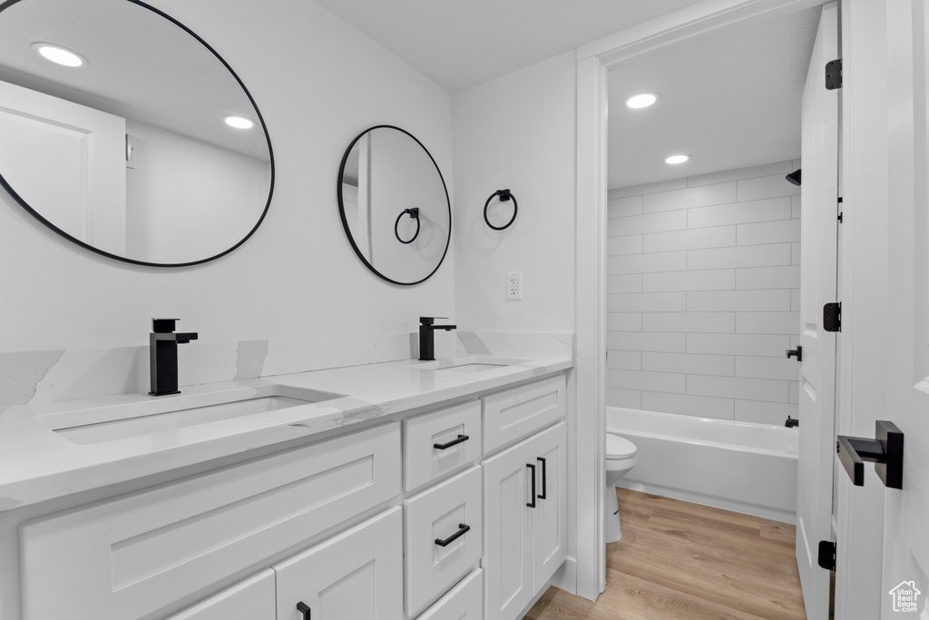 Full bathroom featuring vanity, tiled shower / bath, hardwood / wood-style floors, and toilet