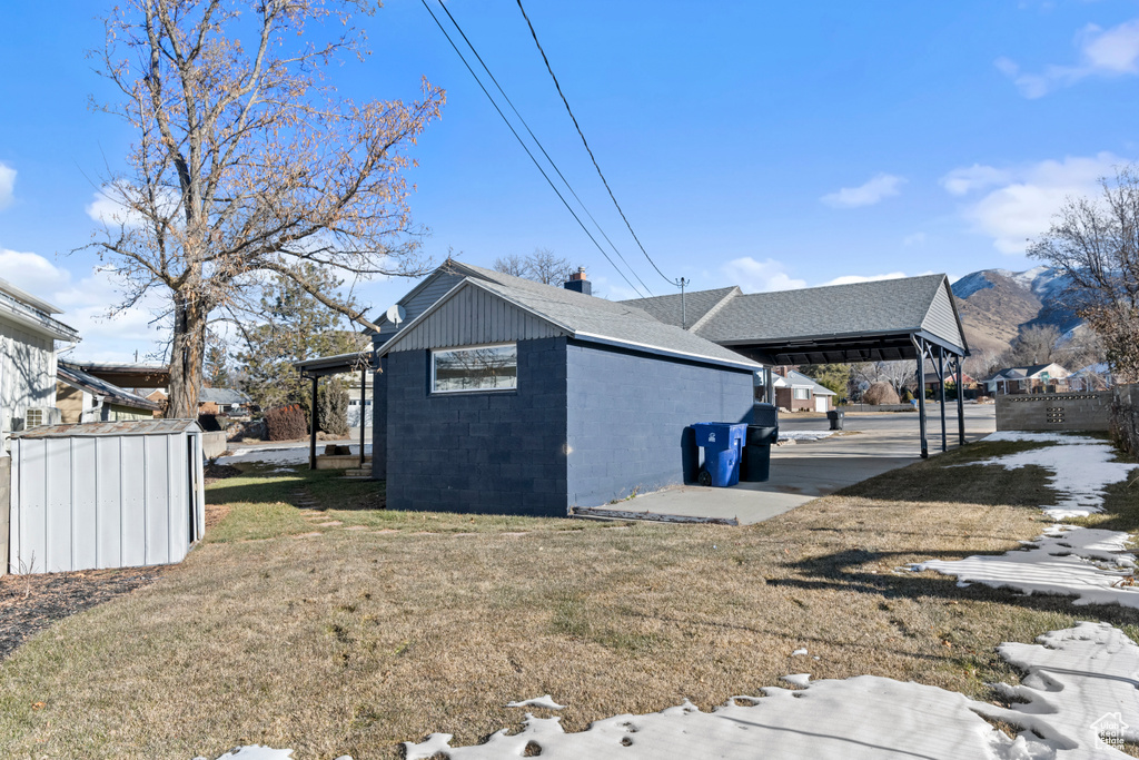 View of home's exterior featuring a carport, a yard, and an outdoor structure