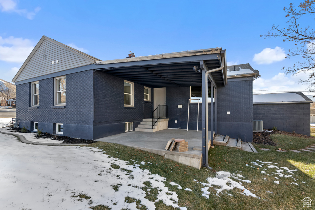 Snow covered house featuring a patio and central air condition unit
