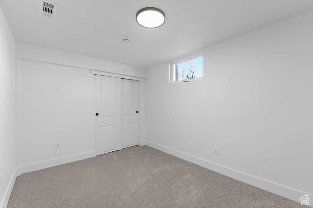 Unfurnished bedroom featuring light carpet and a closet