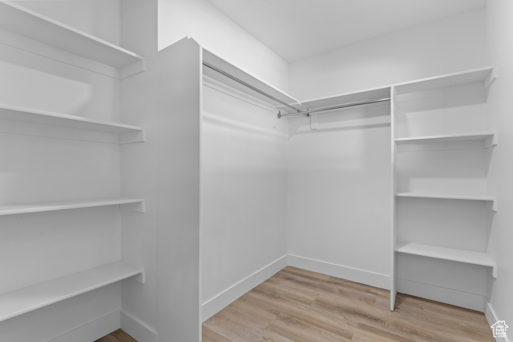 Walk in closet with hardwood / wood-style floors