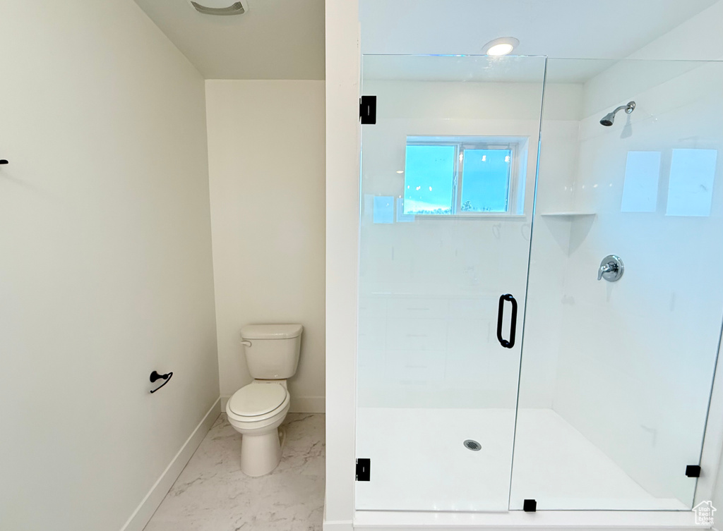 Bathroom with marble finish floor, baseboards, a shower stall, and toilet