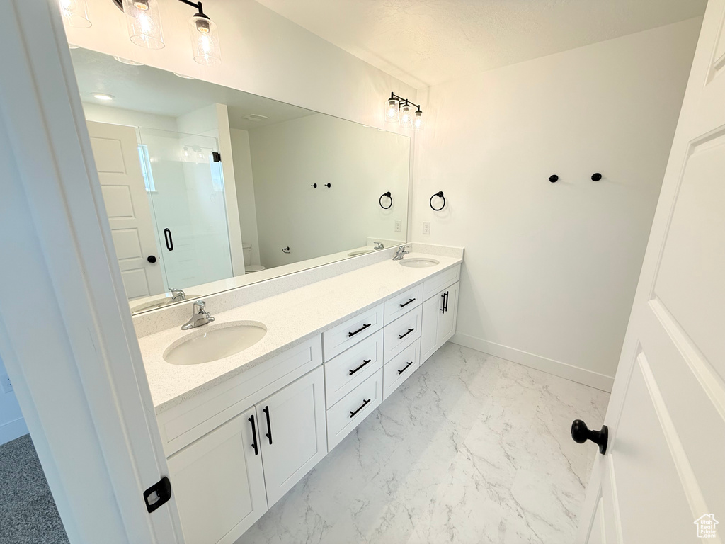 Full bath with marble finish floor, toilet, a stall shower, a sink, and baseboards