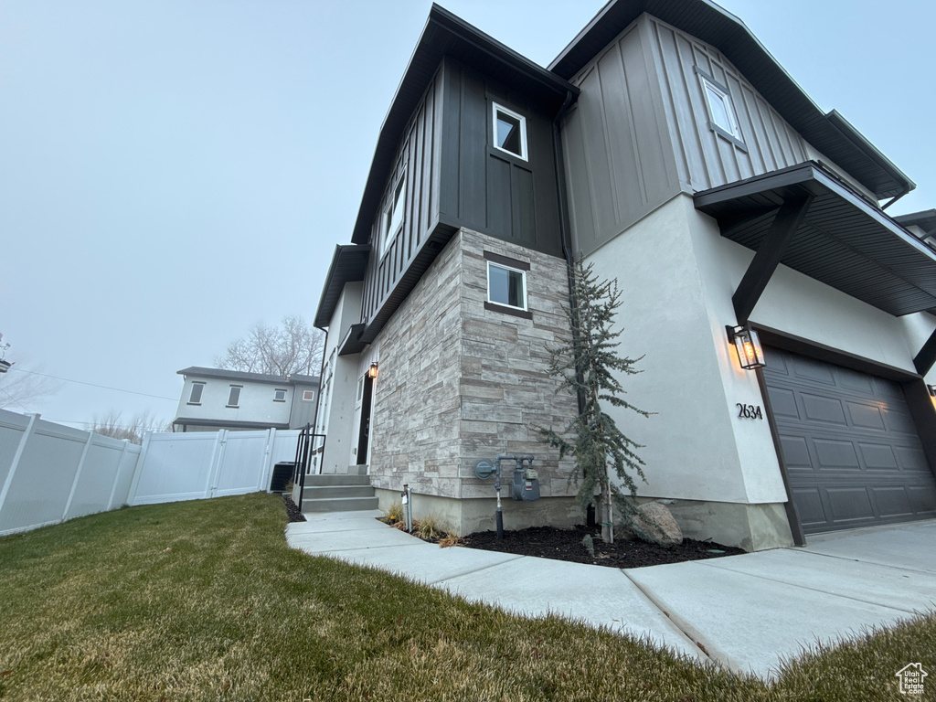 View of side of property featuring a garage and a lawn