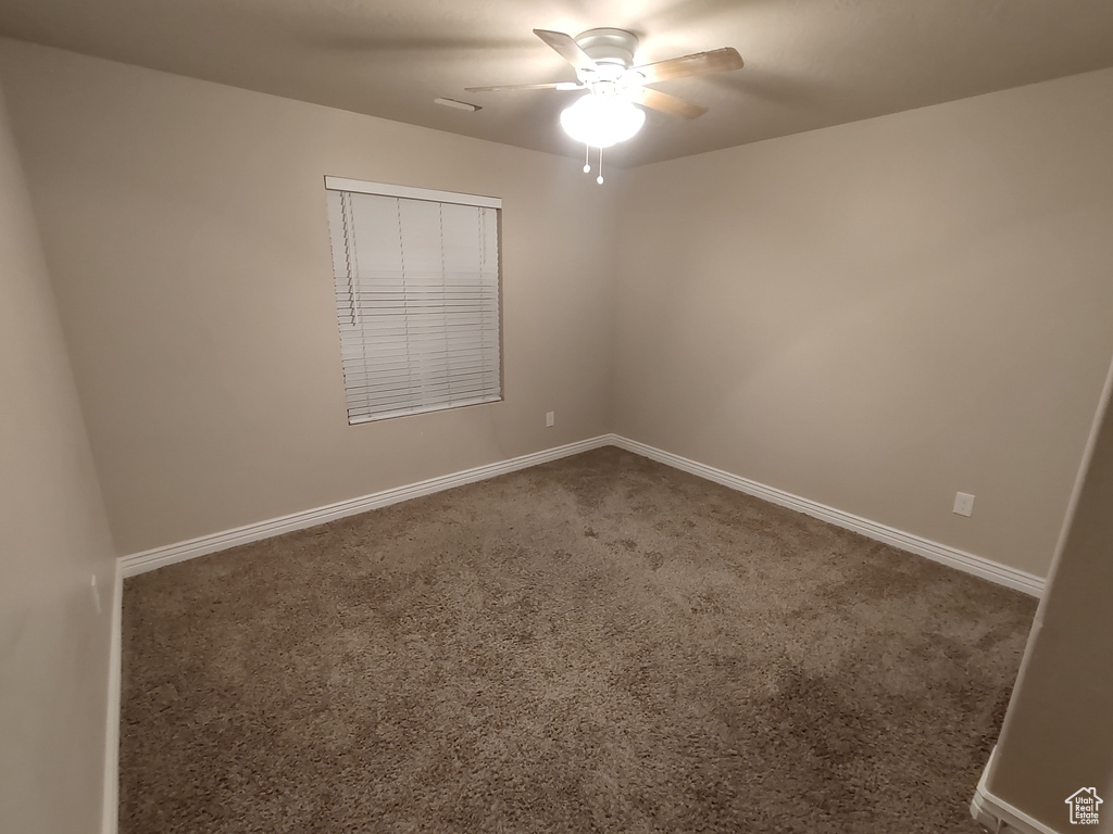Carpeted empty room featuring baseboards and ceiling fan