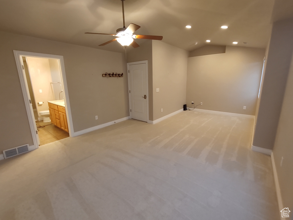 Interior space featuring vaulted ceiling, light colored carpet, visible vents, and ceiling fan