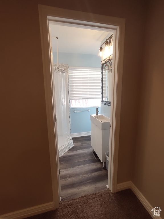 Corridor featuring dark wood-style flooring, baseboards, and a sink