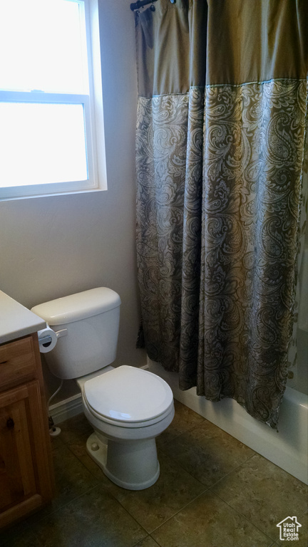 Bathroom with vanity, shower / tub combo, toilet, and tile patterned flooring