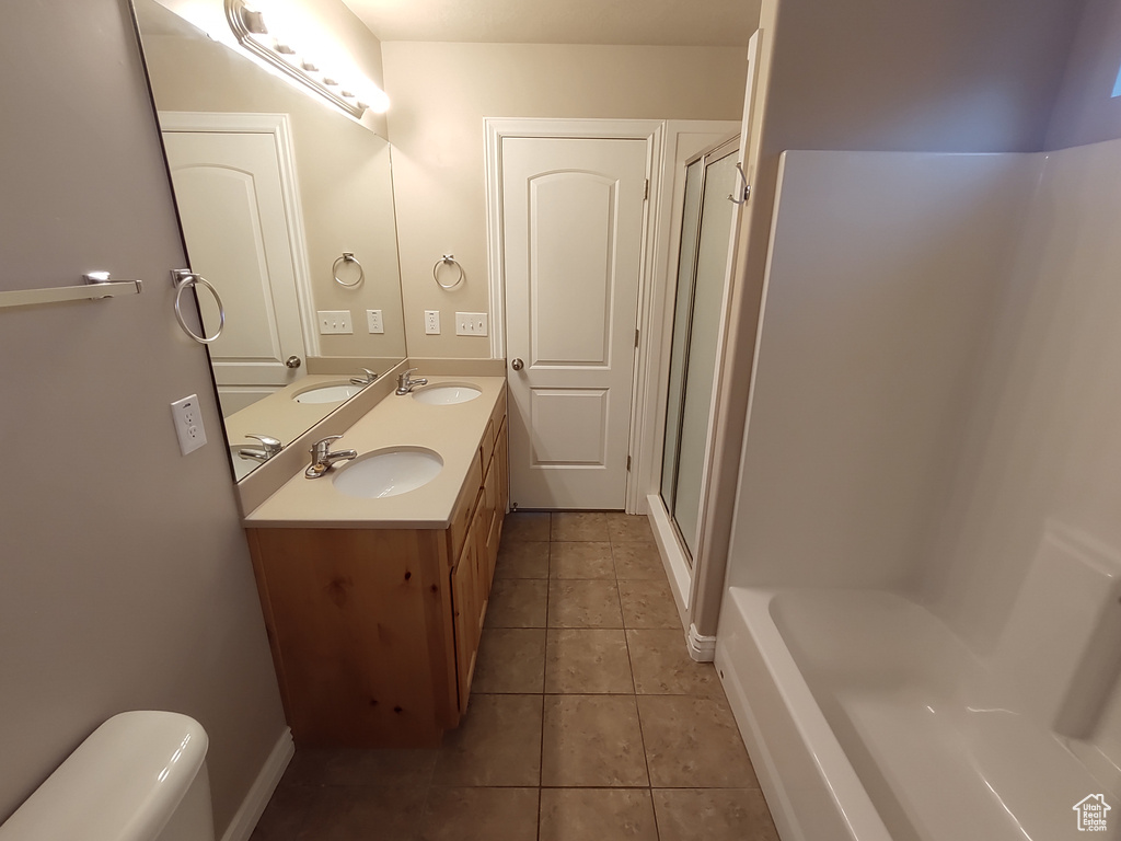 Full bathroom featuring tile patterned floors, a shower with door, and a sink