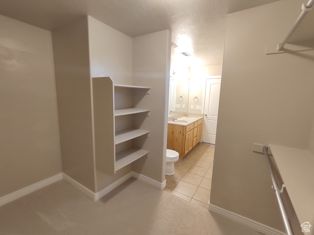 Bathroom with vanity, baseboards, a textured ceiling, tile patterned floors, and toilet