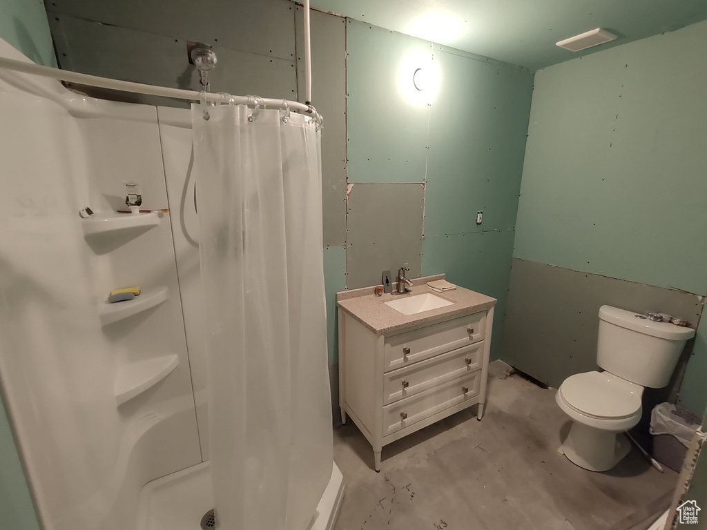 Full bathroom with toilet, a stall shower, vanity, and concrete flooring