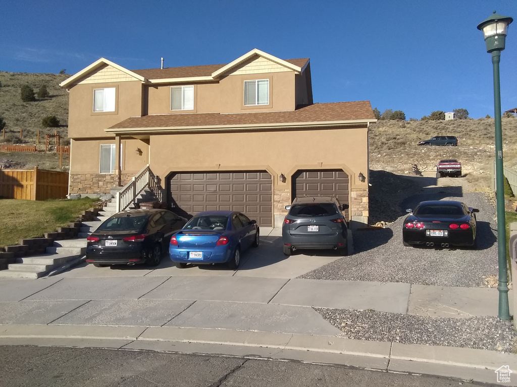 View of front facade featuring stone siding, stucco siding, concrete driveway, and a garage
