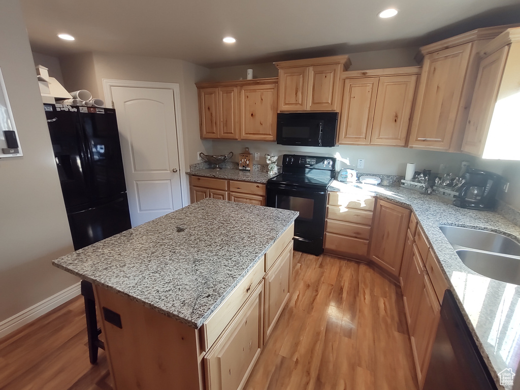 Kitchen featuring recessed lighting, light wood-style flooring, black appliances, and light stone countertops