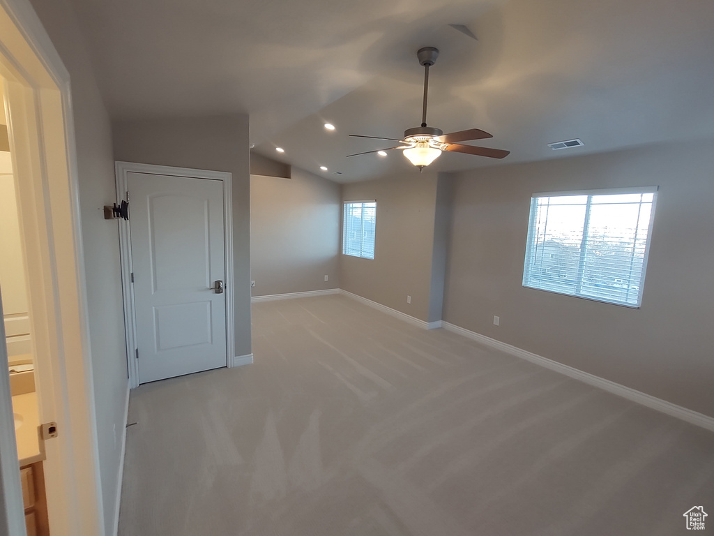 Unfurnished room featuring visible vents, baseboards, light colored carpet, vaulted ceiling, and a ceiling fan