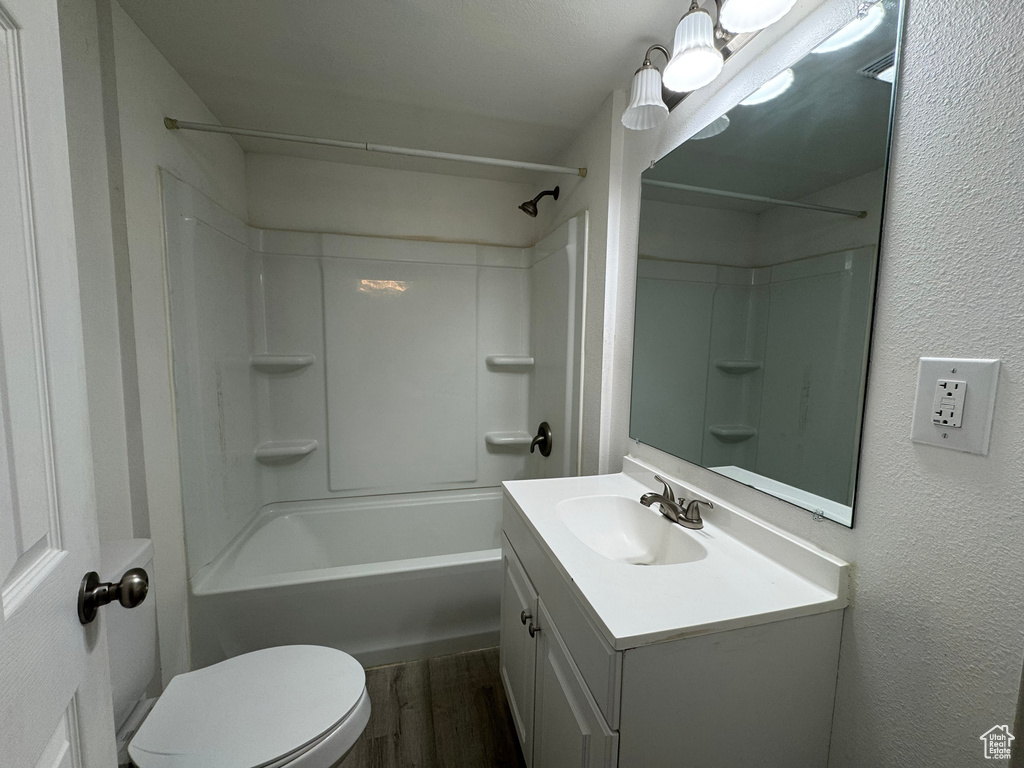 Full bathroom with vanity, toilet, hardwood / wood-style floors, and shower / bathing tub combination
