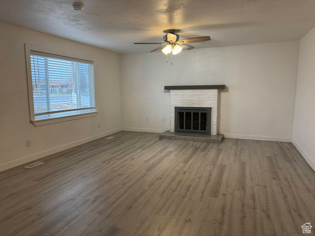 Unfurnished living room featuring ceiling fan, hardwood / wood-style floors, and a fireplace