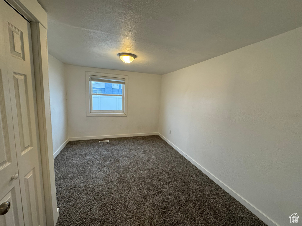 Carpeted empty room featuring a textured ceiling
