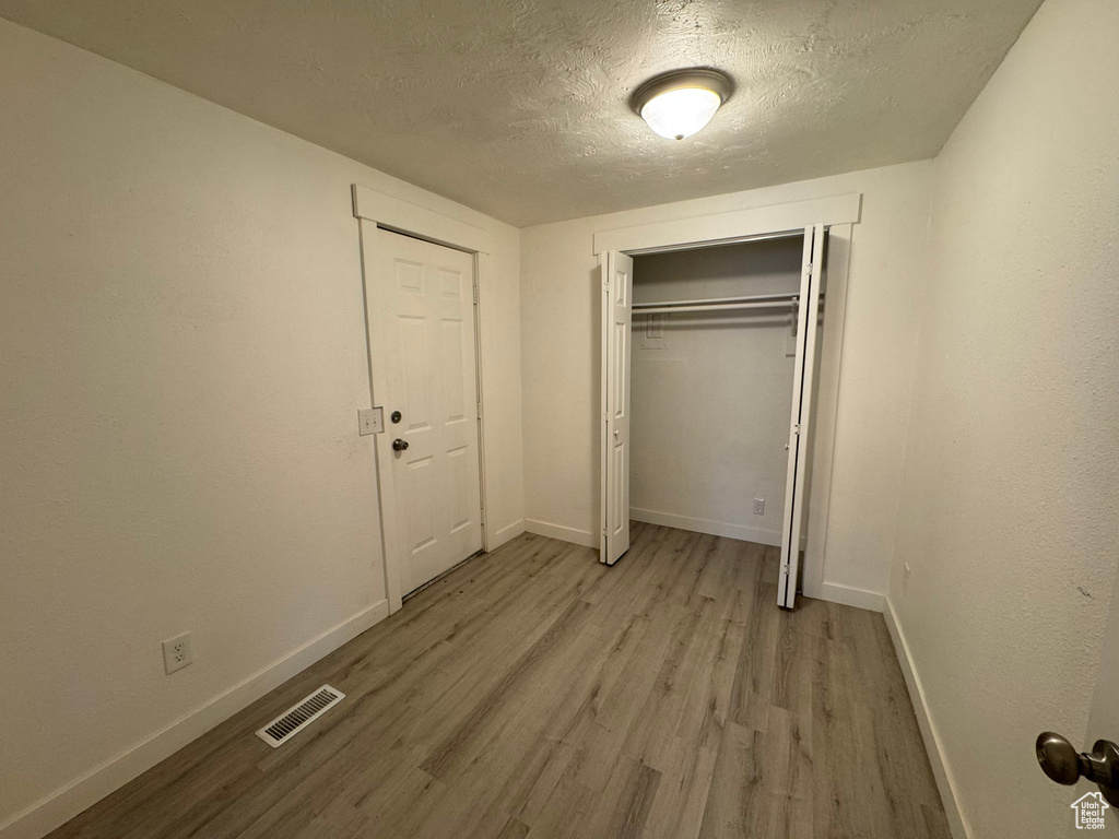 Unfurnished bedroom with a closet, a textured ceiling, and light hardwood / wood-style flooring