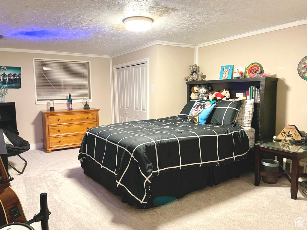 Bedroom with crown molding, carpet floors, a closet, and a textured ceiling