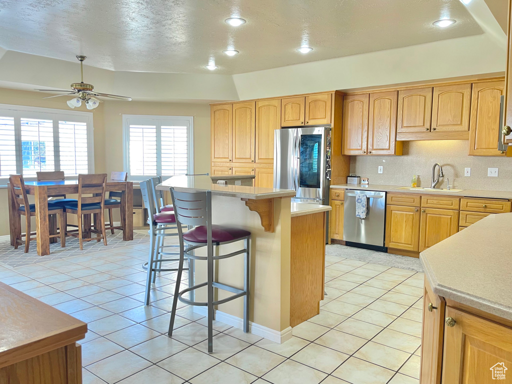 Kitchen featuring sink, appliances with stainless steel finishes, tasteful backsplash, a kitchen island, and a raised ceiling