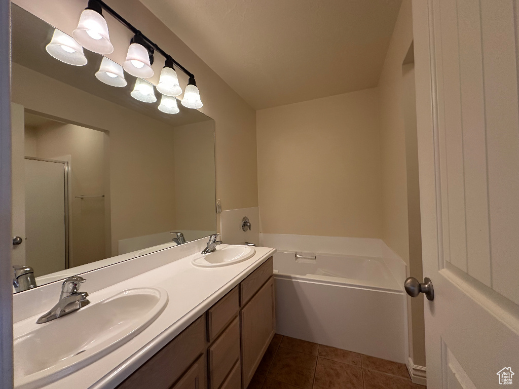 Bathroom with vanity, tile patterned flooring, and a washtub