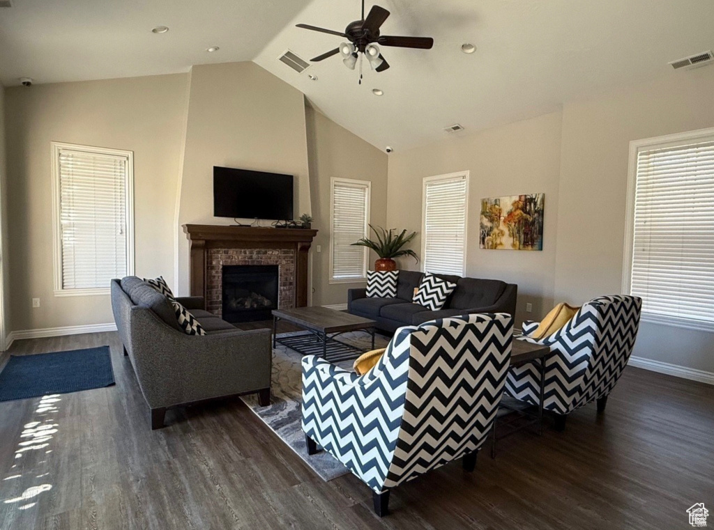 Living room with a brick fireplace, dark hardwood / wood-style floors, high vaulted ceiling, and ceiling fan