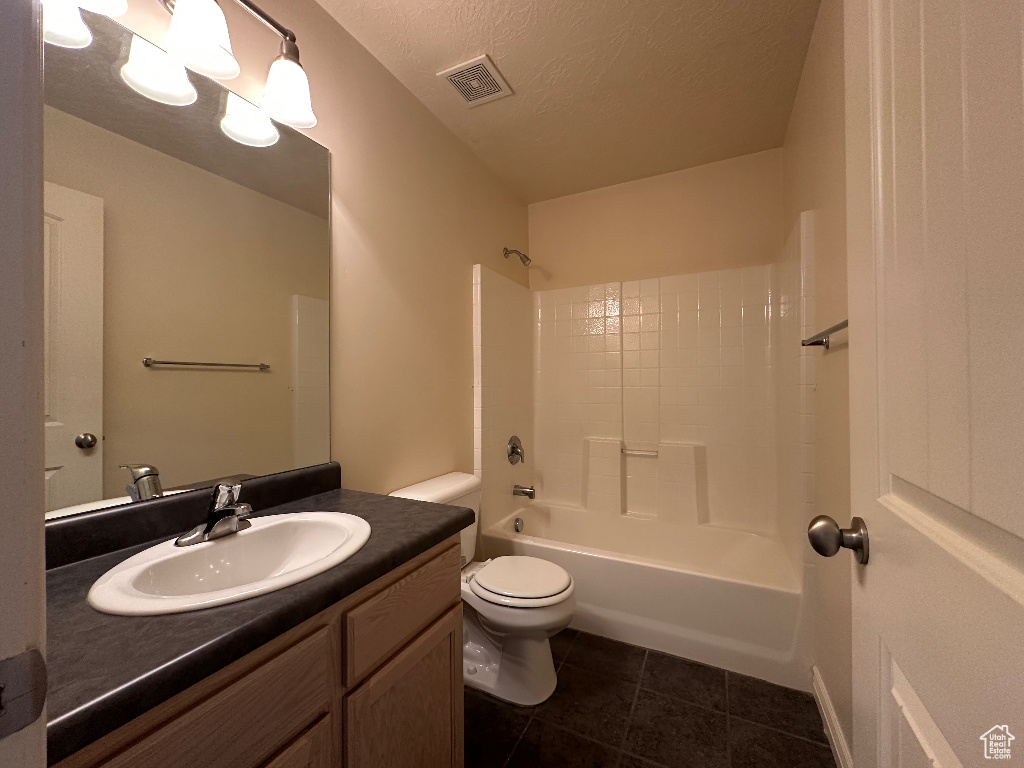 Full bathroom featuring tile patterned floors, toilet, bathing tub / shower combination, a textured ceiling, and vanity