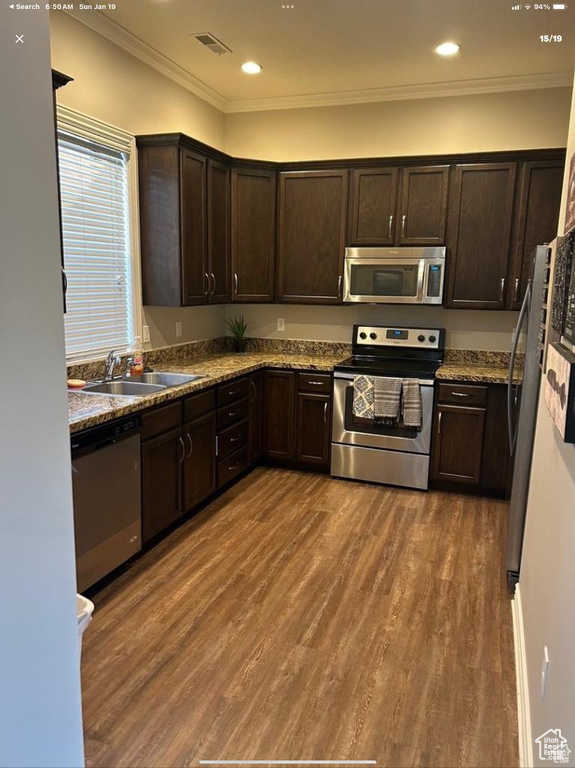 Kitchen with sink, dark wood-type flooring, stone counters, dark brown cabinets, and stainless steel appliances