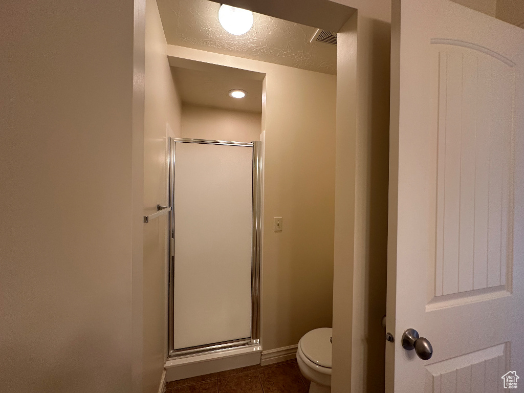 Bathroom featuring a textured ceiling, toilet, and walk in shower