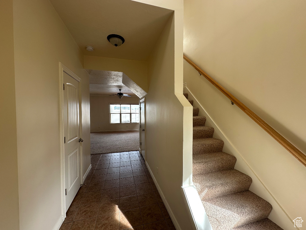 Staircase with ceiling fan and tile patterned floors