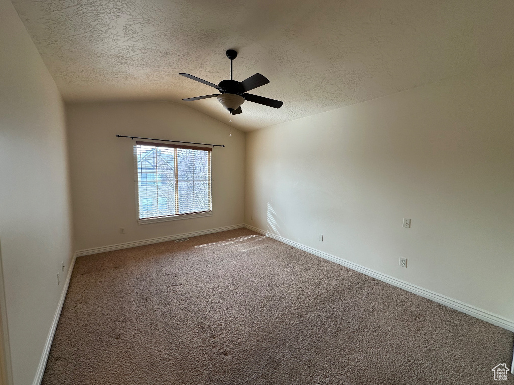 Carpeted spare room with ceiling fan, lofted ceiling, and a textured ceiling