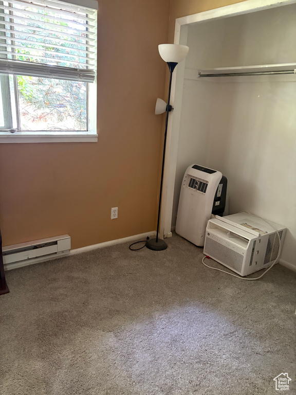 Unfurnished bedroom with a baseboard heating unit, multiple windows, and carpet
