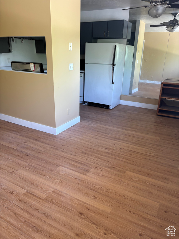Unfurnished living room featuring ceiling fan, light wood-style flooring, and baseboards