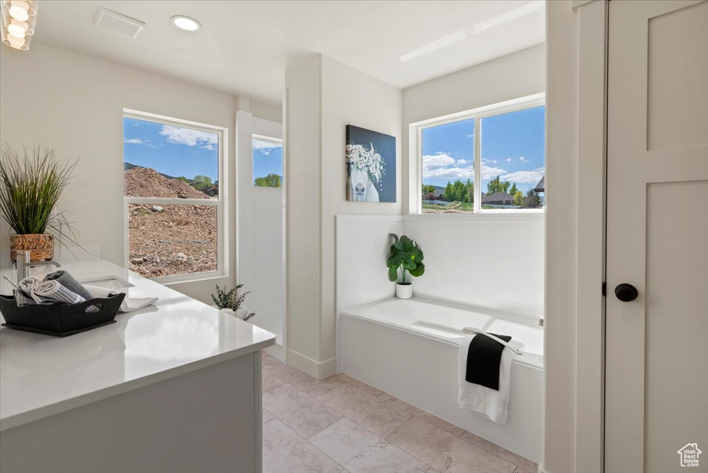 Full bath featuring marble finish floor, a wealth of natural light, a garden tub, and recessed lighting