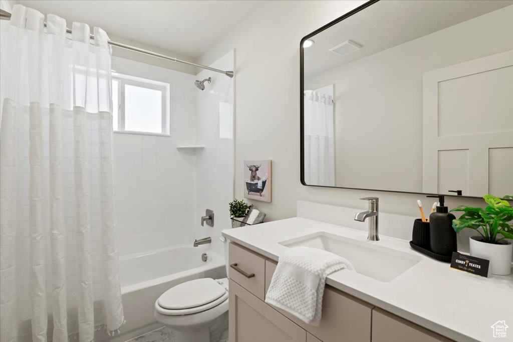 Bathroom featuring toilet, visible vents, vanity, and shower / bath combination with curtain