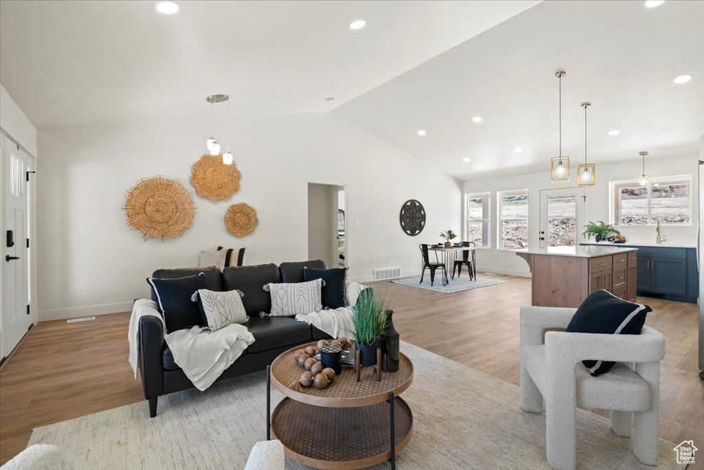 Living area with light wood finished floors, vaulted ceiling, and recessed lighting