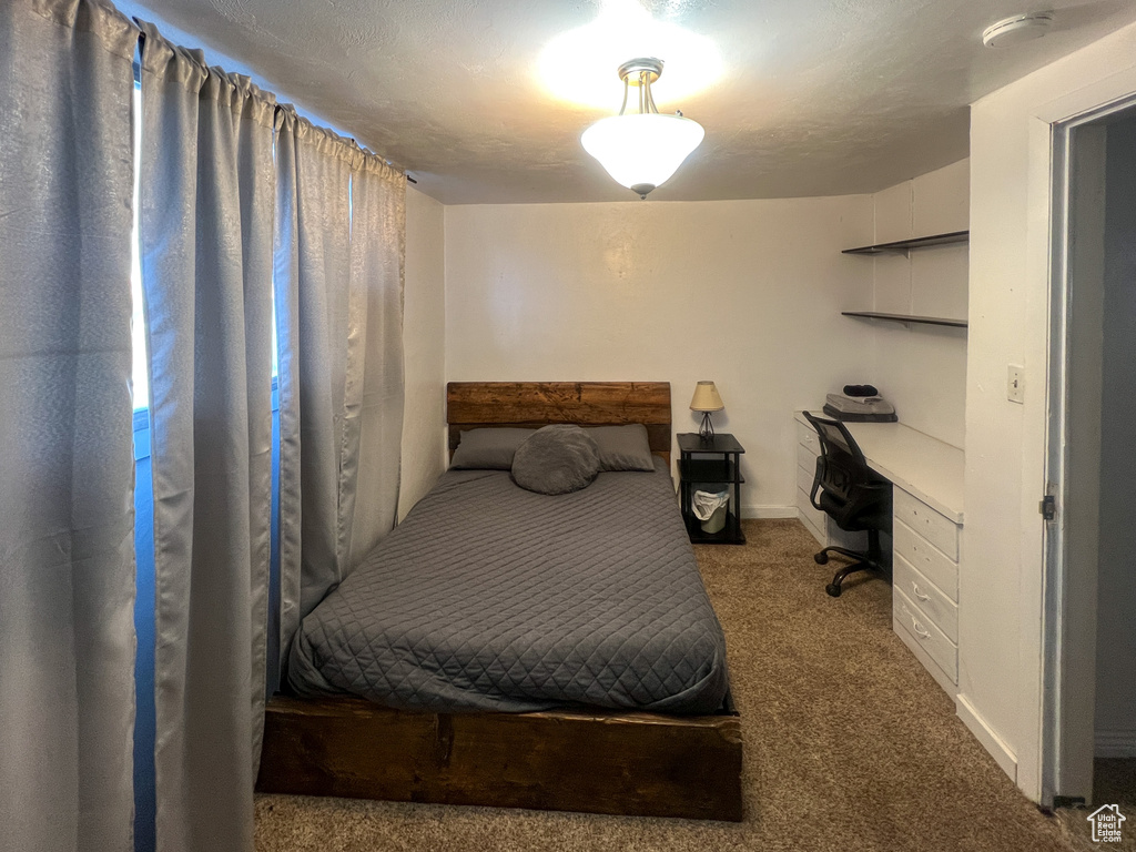 Carpeted bedroom featuring built in desk