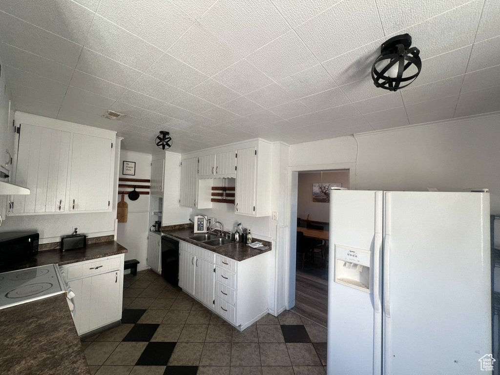 Kitchen with sink, black dishwasher, white fridge with ice dispenser, and white cabinets