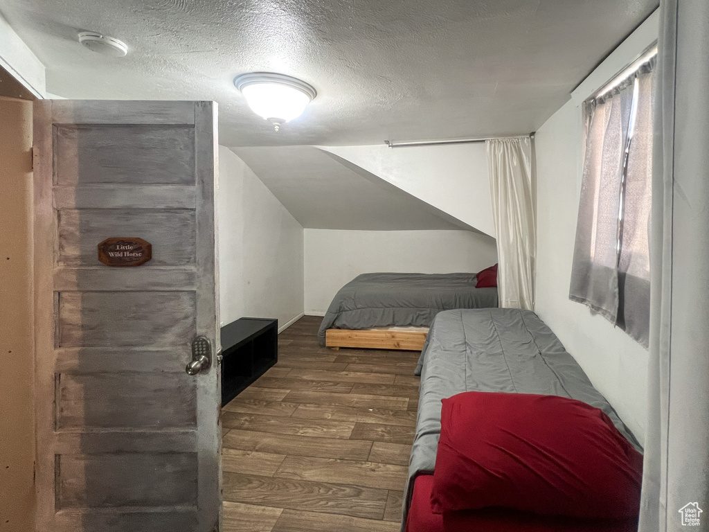 Bedroom featuring lofted ceiling, dark hardwood / wood-style floors, and a textured ceiling