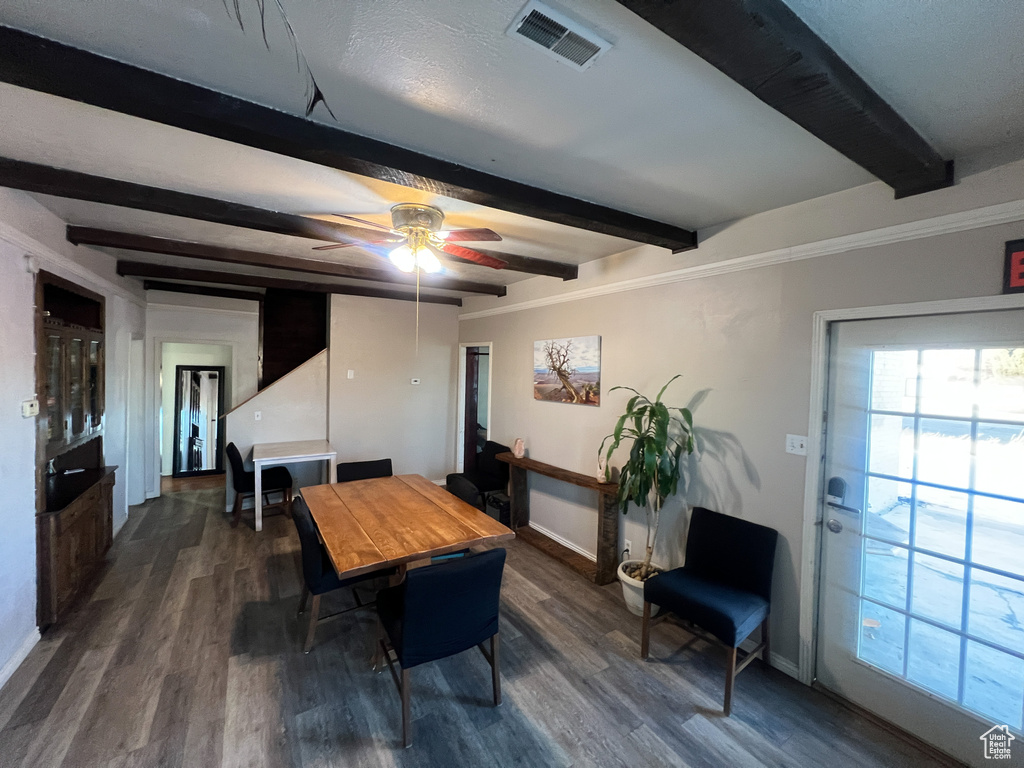 Dining room featuring dark wood-type flooring, ceiling fan, beam ceiling, and crown molding